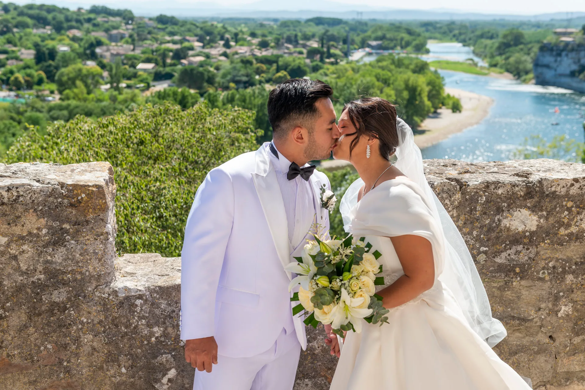 Les mariés s'embrassent sur une terrasse en pierre surplombant le paysage provençal
