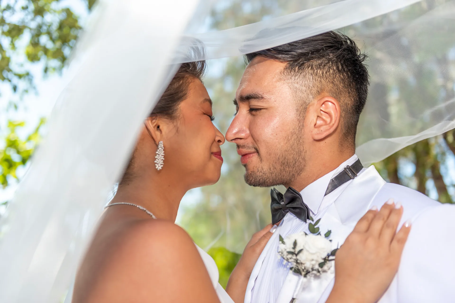 Un couple de mariés se rapproche sous le voile de la mariée dans un jardin