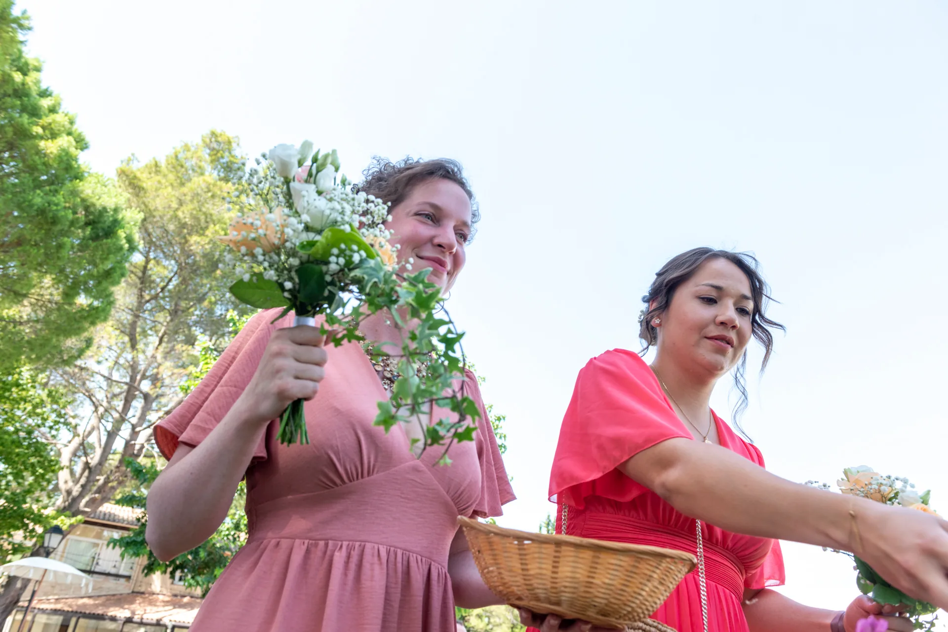 Deux demoiselles d’honneur portent leurs bouquets pendant une cérémonie en extérieur