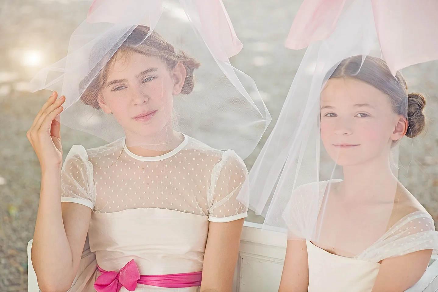 Deux demoiselles d’honneur portant des voiles blancs dans une lumière douce