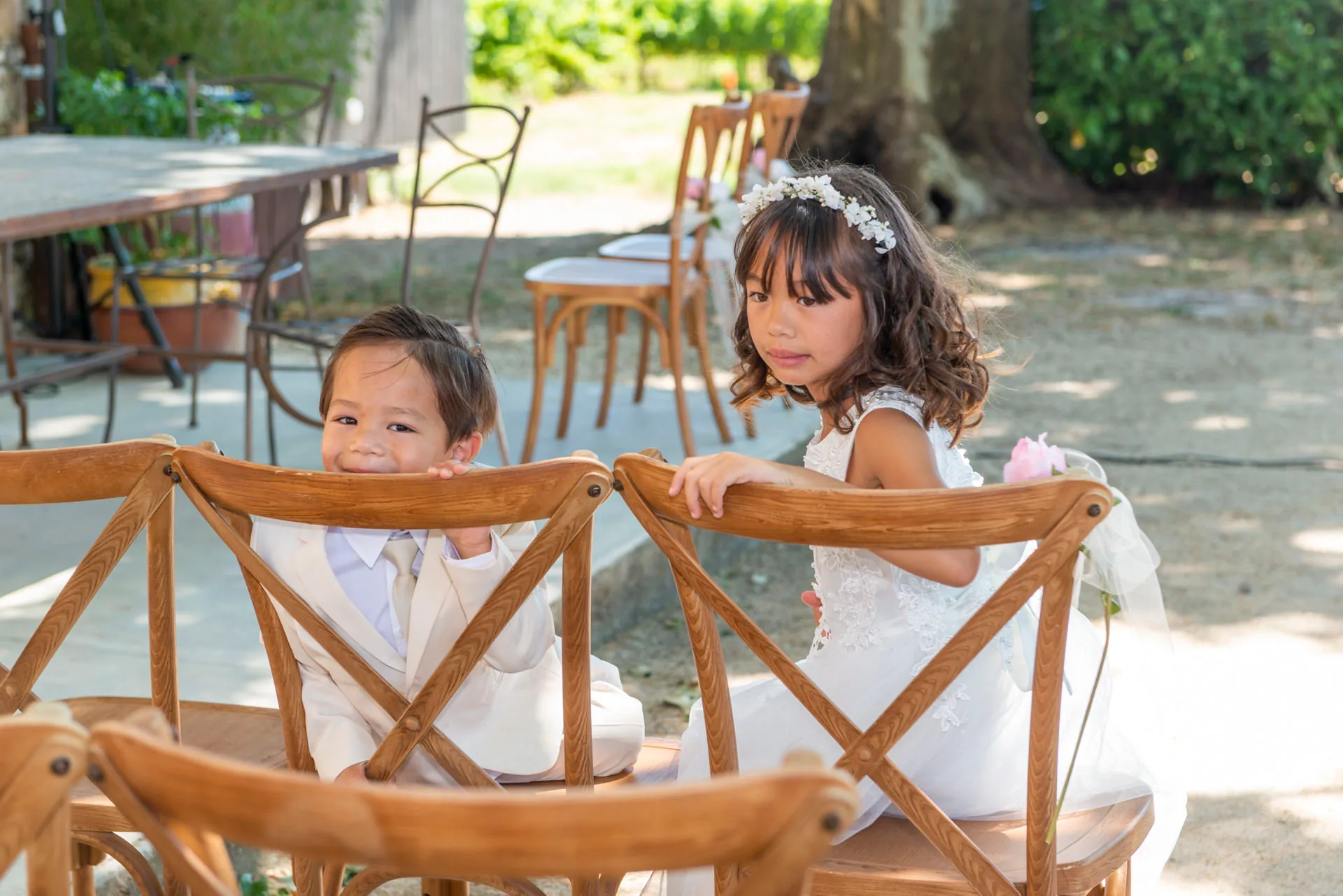 Les enfants d'honneur assis sur des chaises en bois dans le jardin du domaine