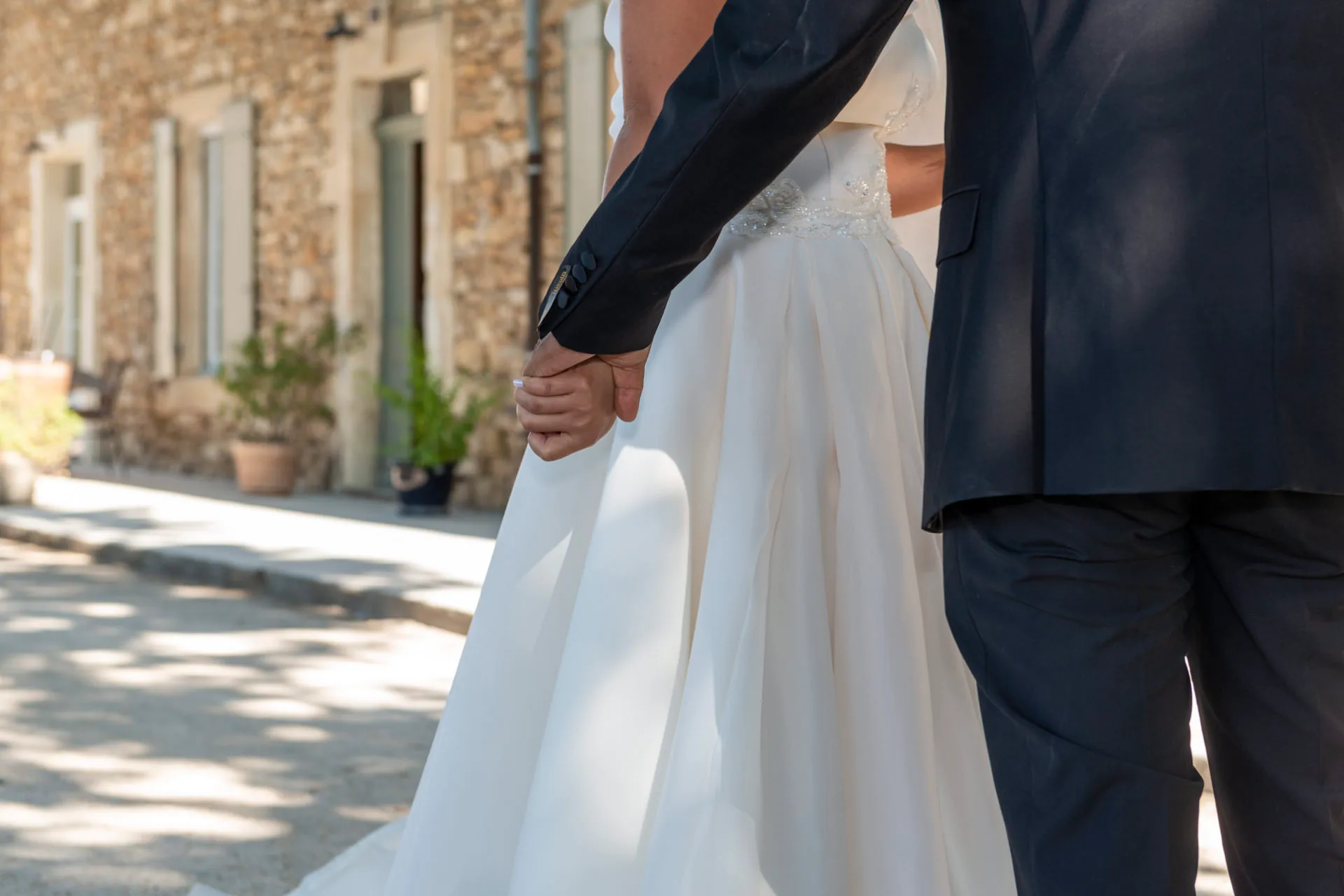 Le marié tient la main de la mariée, la robe se soulevant en marchant