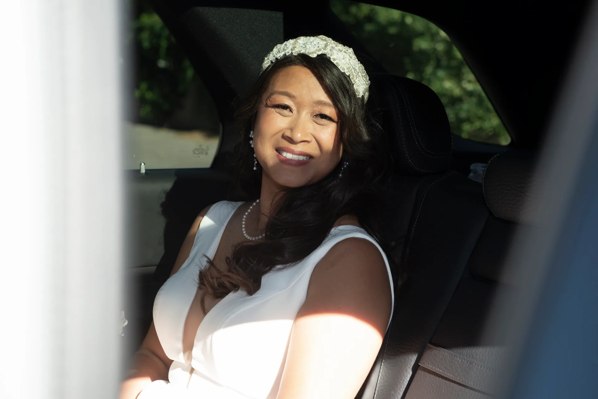 La mariée sourit dans la voiture, coiffée d'une couronne de fleurs avant la cérémonie