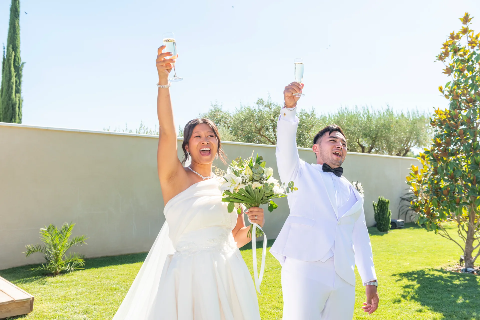 Des mariés lèvent leurs coupes de champagne dans un jardin en Provence