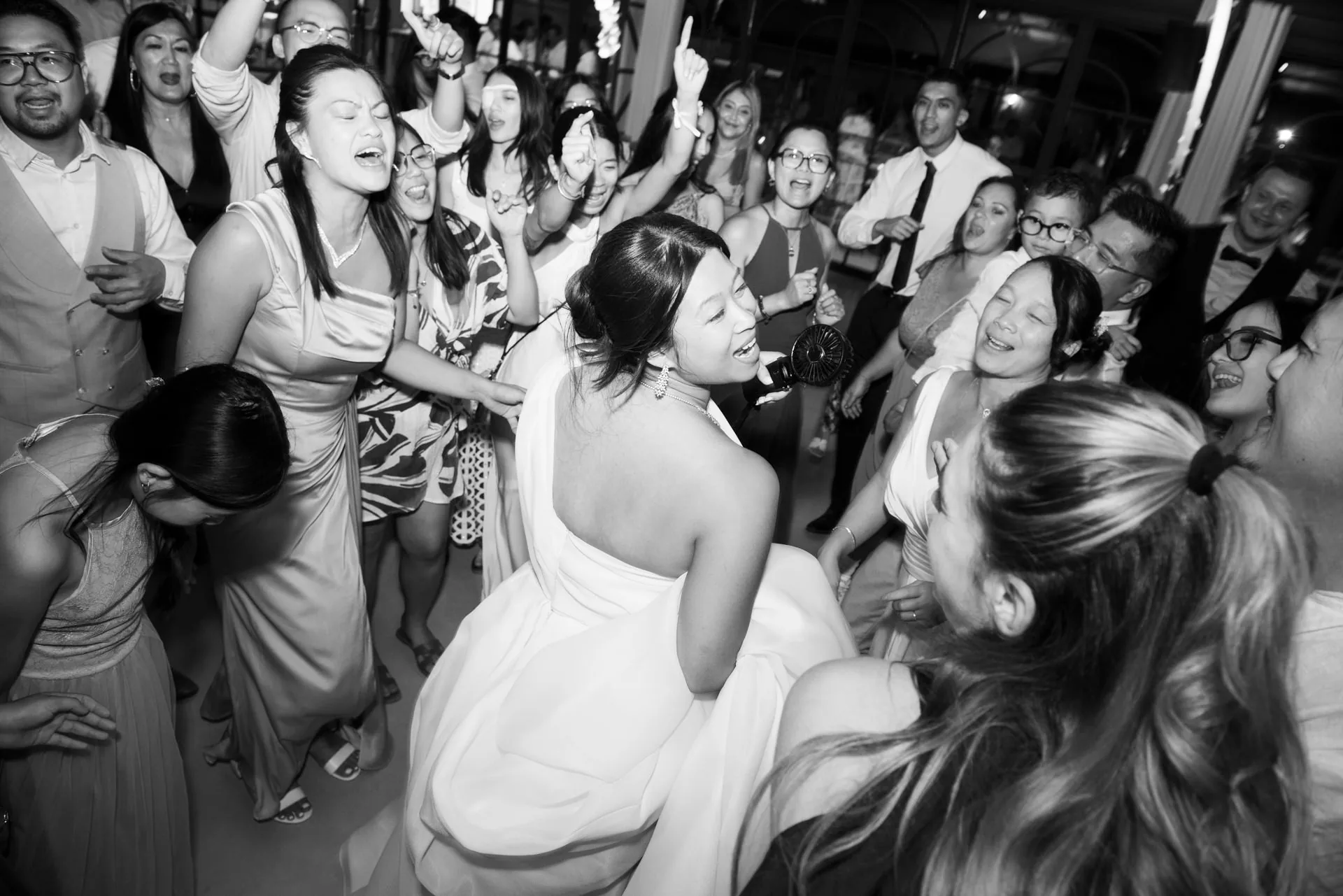 La mariée danse au milieu de ses invités survoltés, en noir et blanc