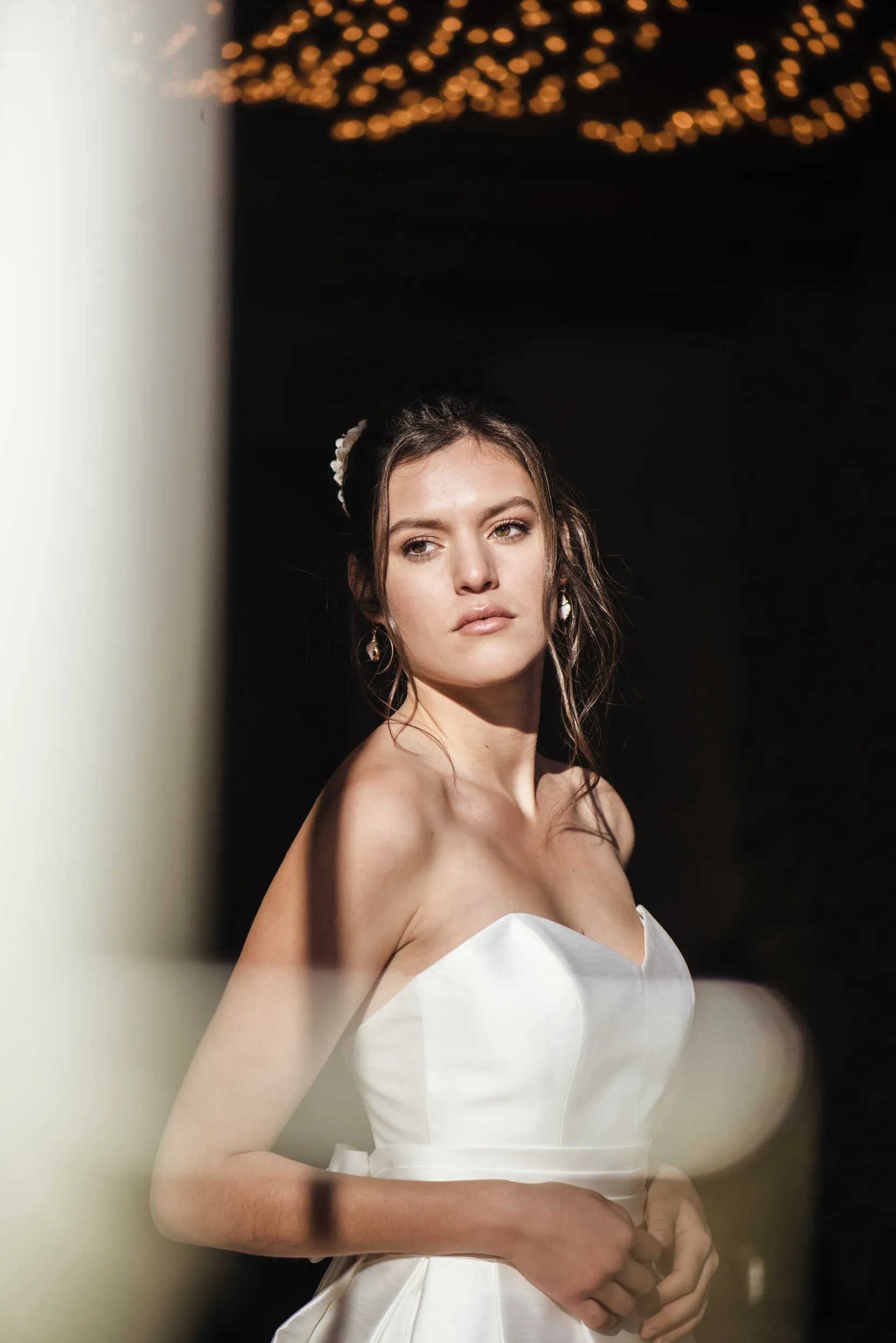 Portrait de la mariée éclairée par le soleil devant un arrière-plan sombre