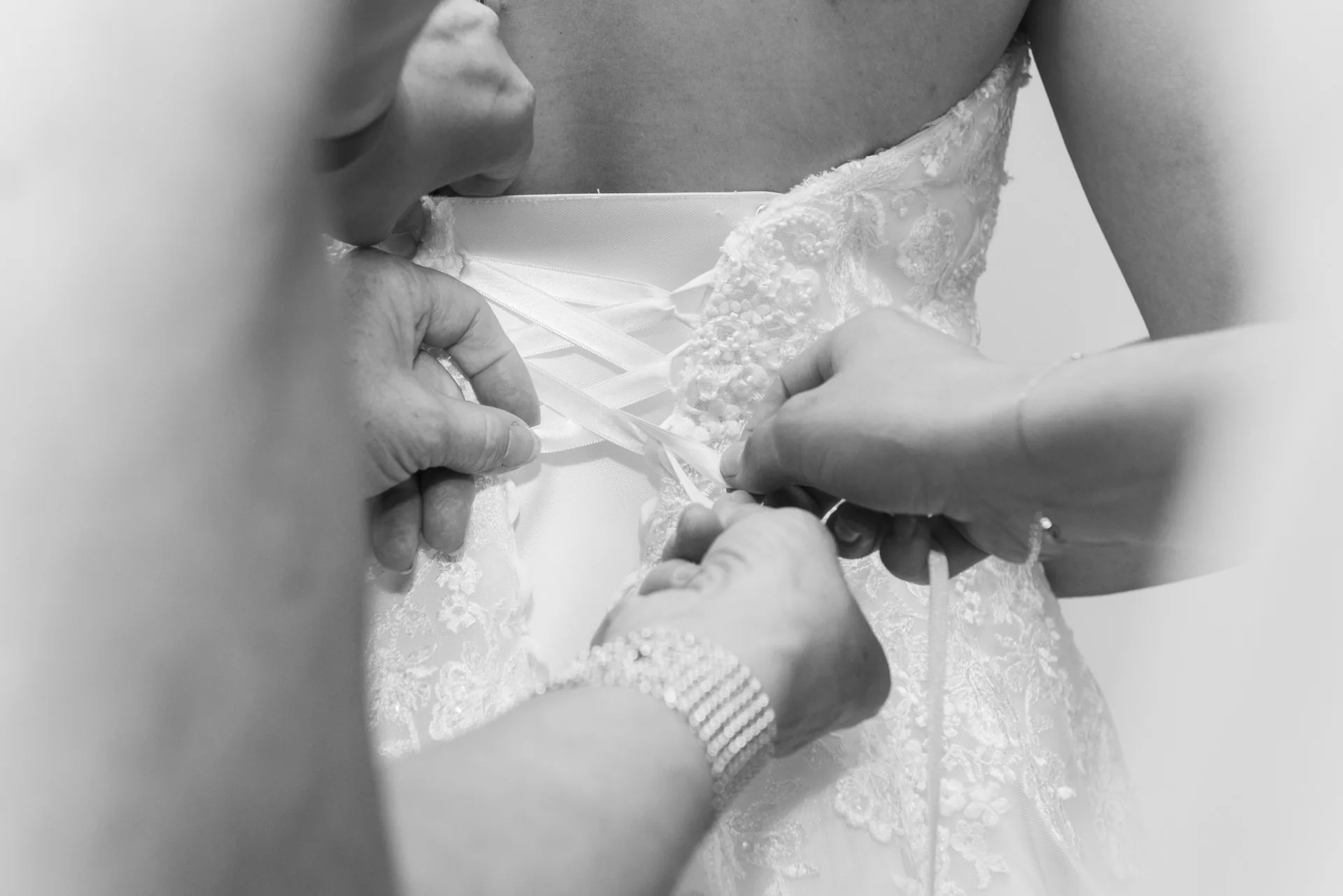 Des proches ajustent le laçage de la robe de mariée