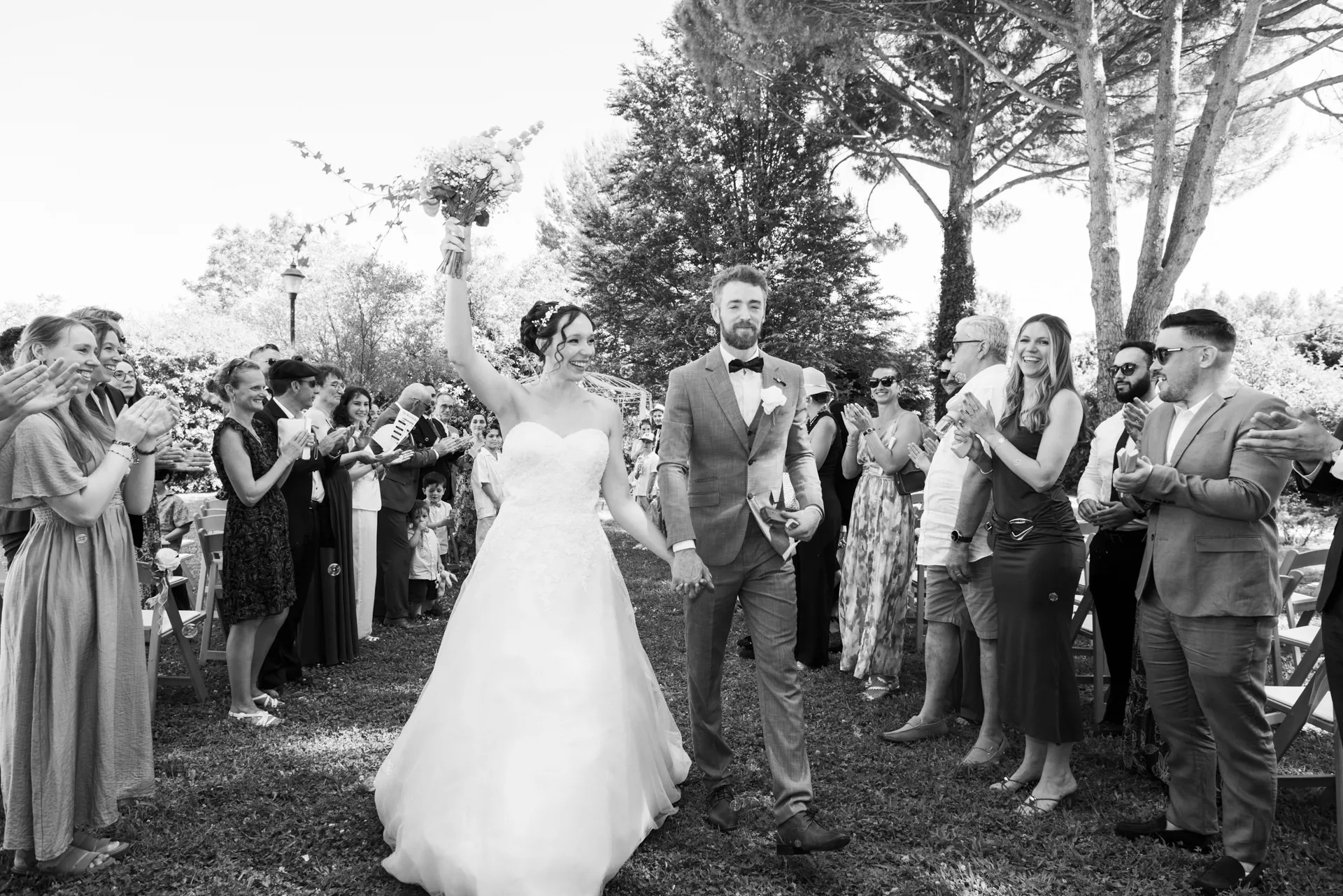 Les mariés quittent la cérémonie sous les applaudissements, la mariée levant son bouquet