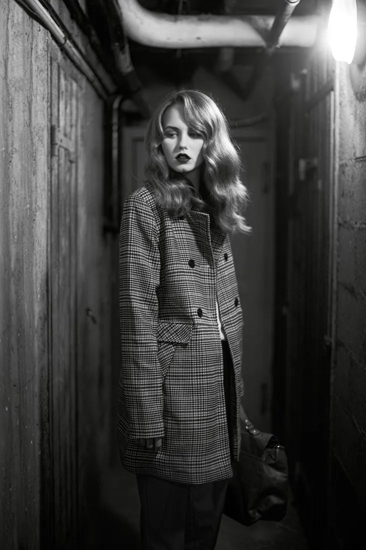 Modèle photographiée en noir et blanc dans un couloir pour un éditorial de mode